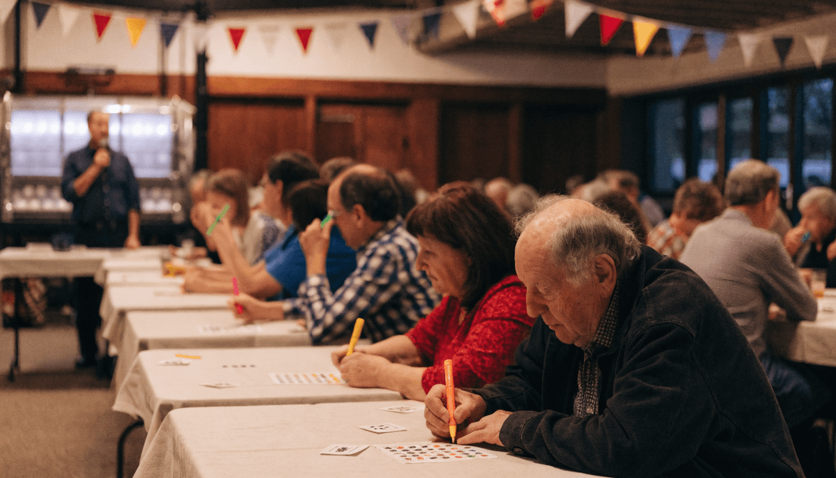 Players of all ages marking bingo cards at a lively club hall bingo night